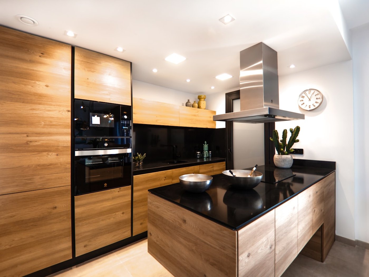 Moderne Küche mit Holzfronten, Kochinsel und dunkler Arbeitsplatte