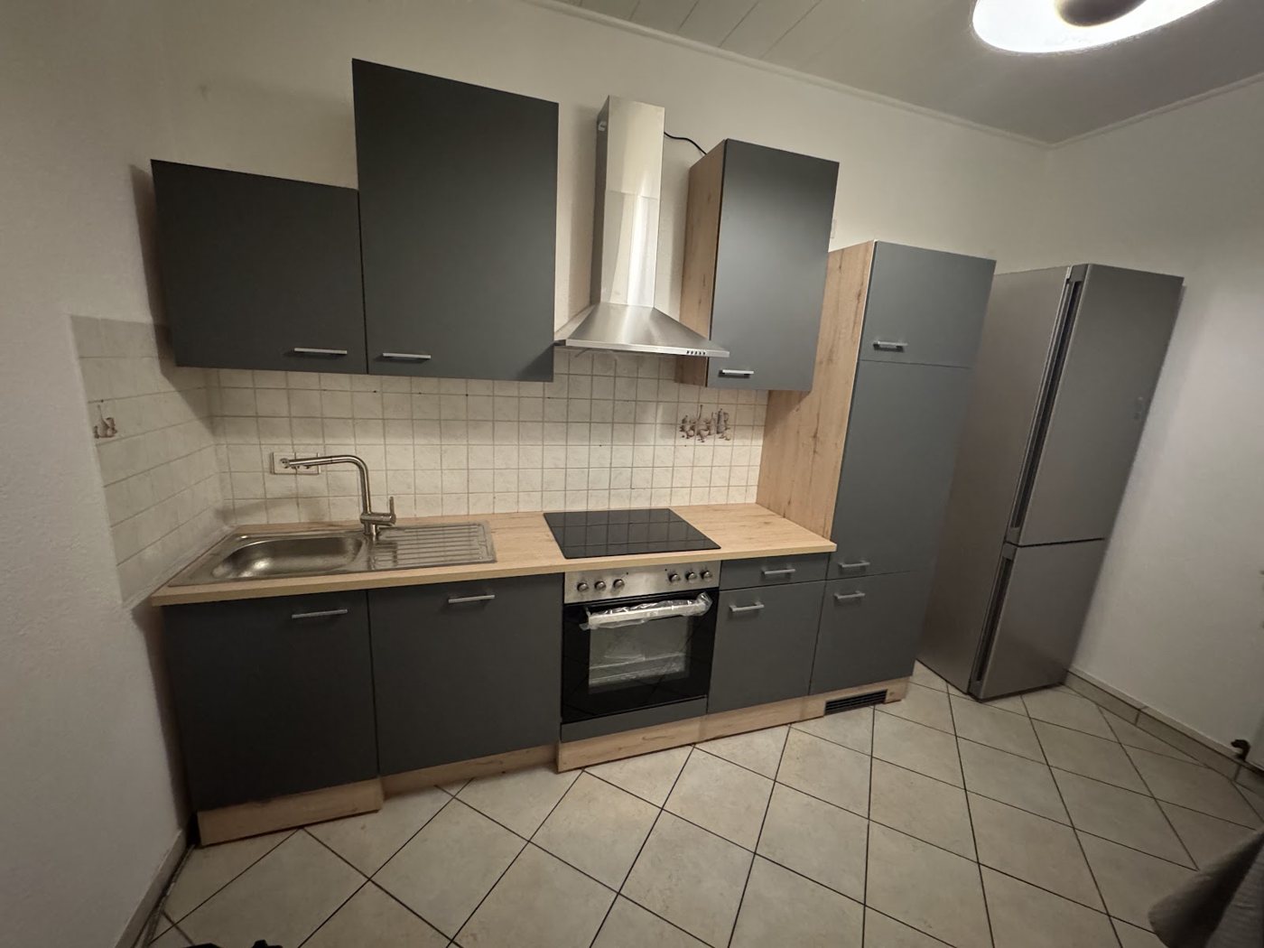 Neue anthrazitfarbene Küchenzeile mit Hochschrank im selben Raum