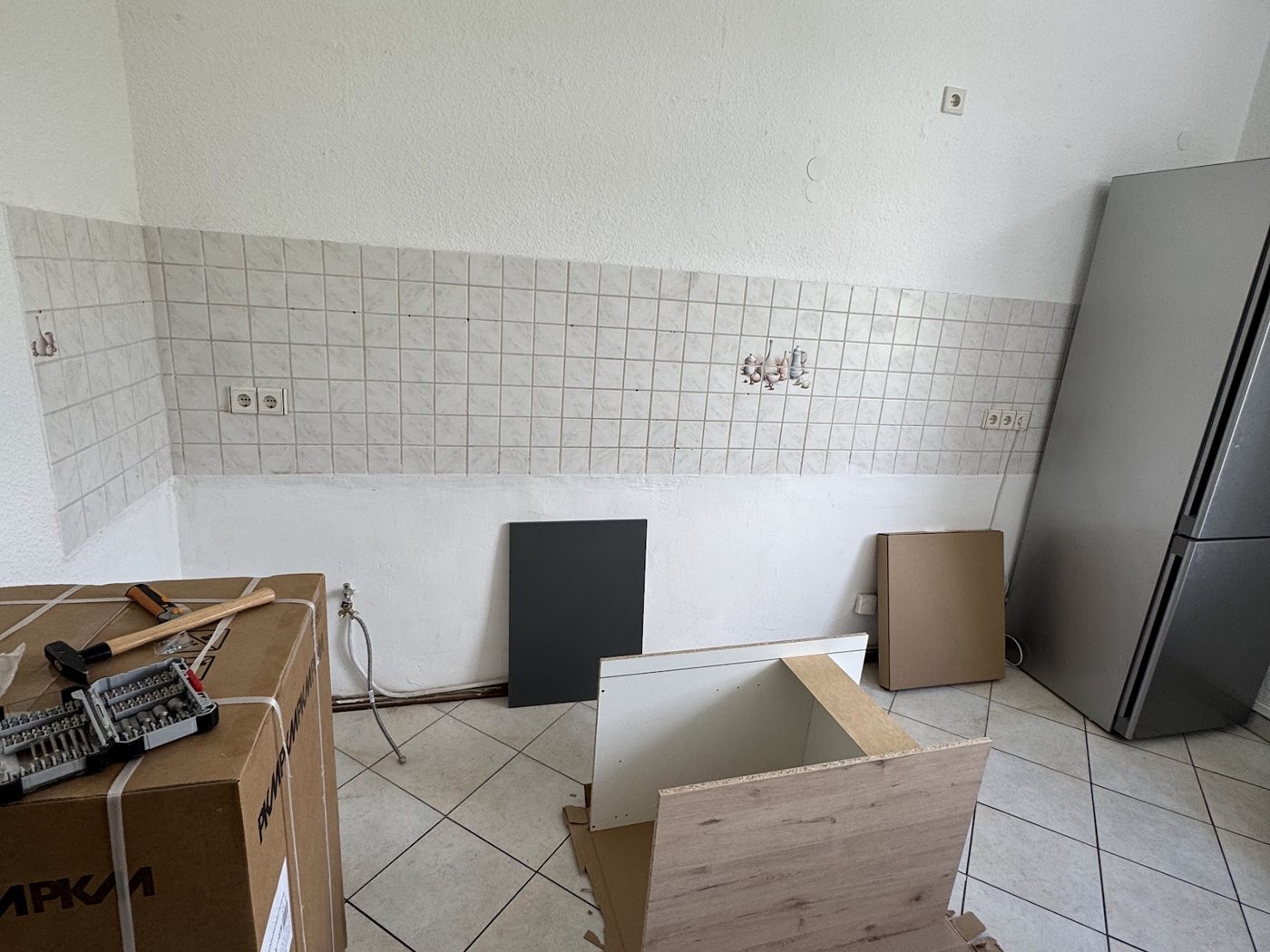 Leerer Küchenraum mit Fliesenspiegel und Kartons auf dem Boden